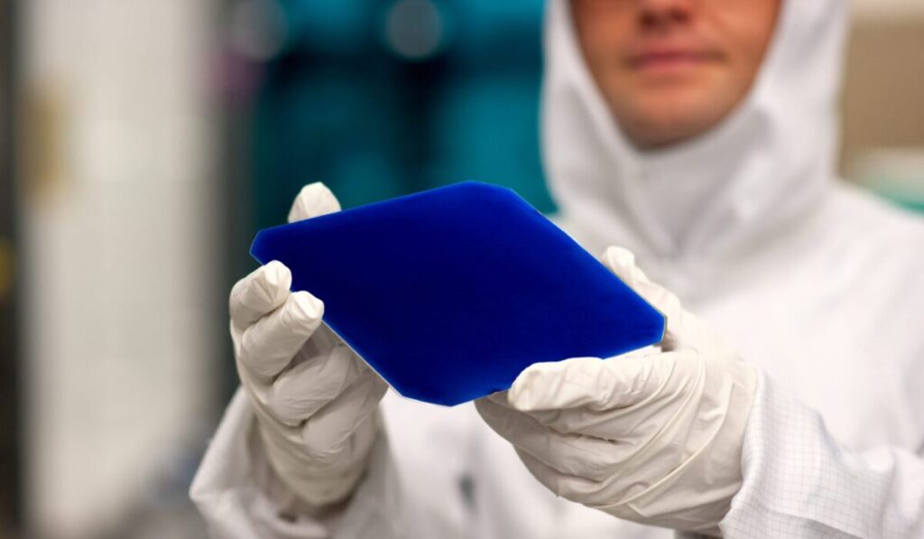 Labortechniker hält eine Solarzelle in den Händen; Forschung, Industrie