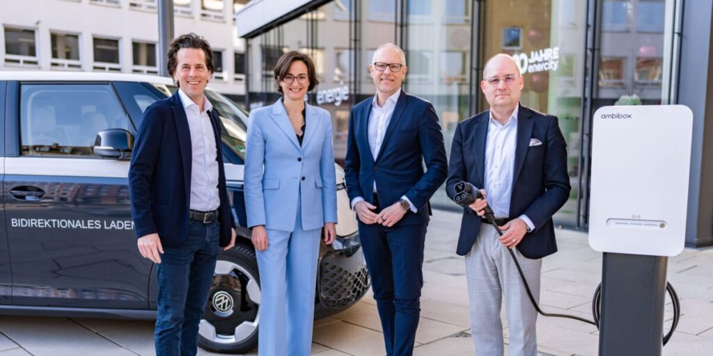 Vier Menschen von enercity ambicobox und VW sonniges Foto strahlende Menschen Elektrotranspoert uim Hinter grudn LAdesäule im Vordergrund