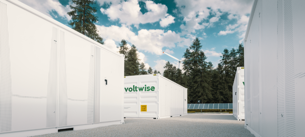 Batteriespeicher von Voltwise Power, mit Windkraftanlagen im Hintergrund