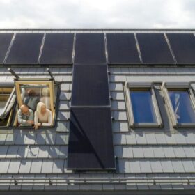 Älteres Ehepaar schaut aus dem Dachfenster ihres Hauses