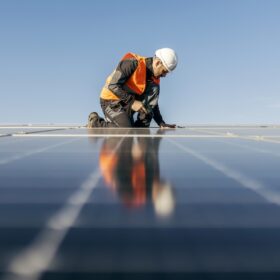 A handyman on the rooftop installing solar panels.