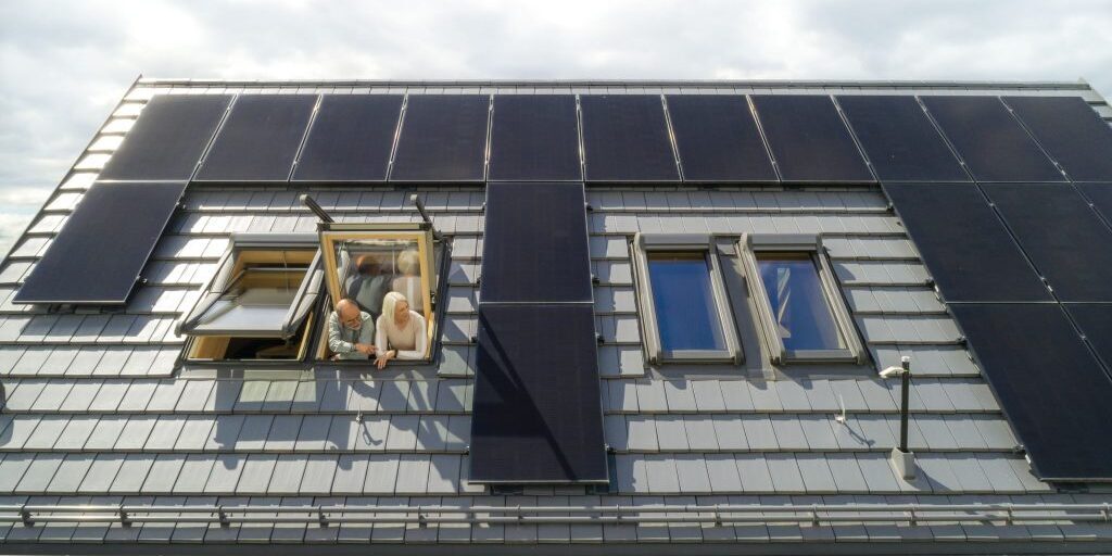 Älteres Ehepaar schaut aus dem Dachfenster ihres Hauses