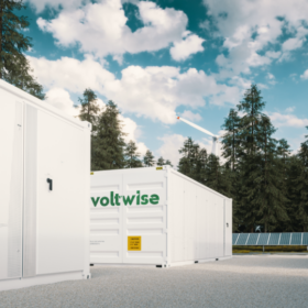 Batteriespeicher von Voltwise Power, mit Windkraftanlagen im Hintergrund